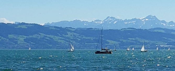 See mit Schiff und Bergen im Hintergrund