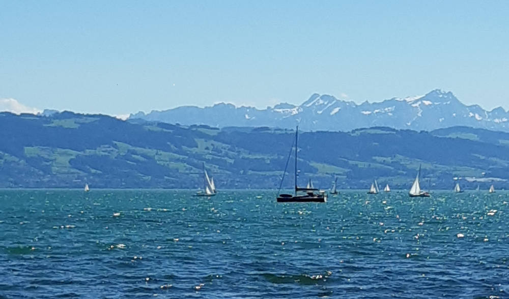 See mit Schiff und Bergen im Hintergrund