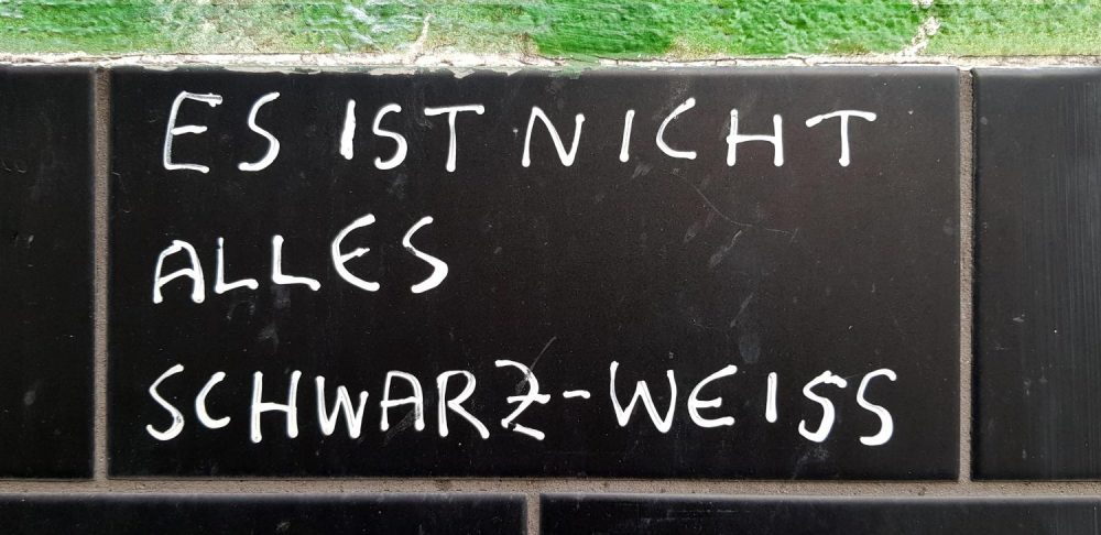 Schwarze Tafel mit der Aufschrift "Es ist nicht alles Schwarz-Weiss"