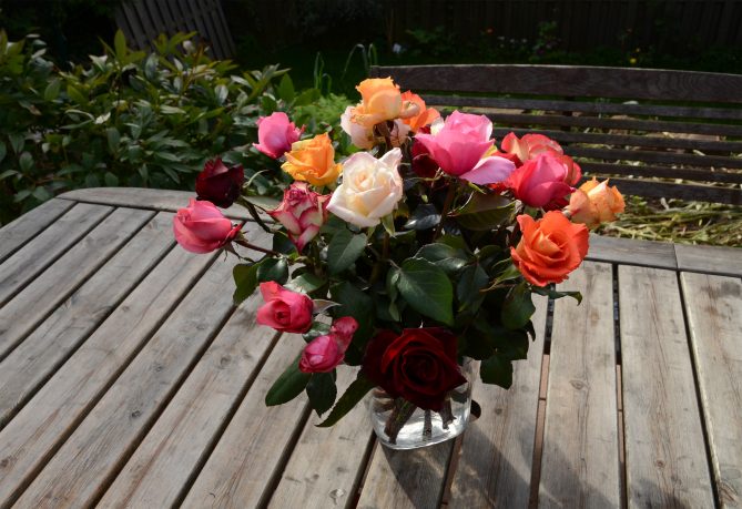 ein bunter Blumenstrauß steht auf einem Holztisch