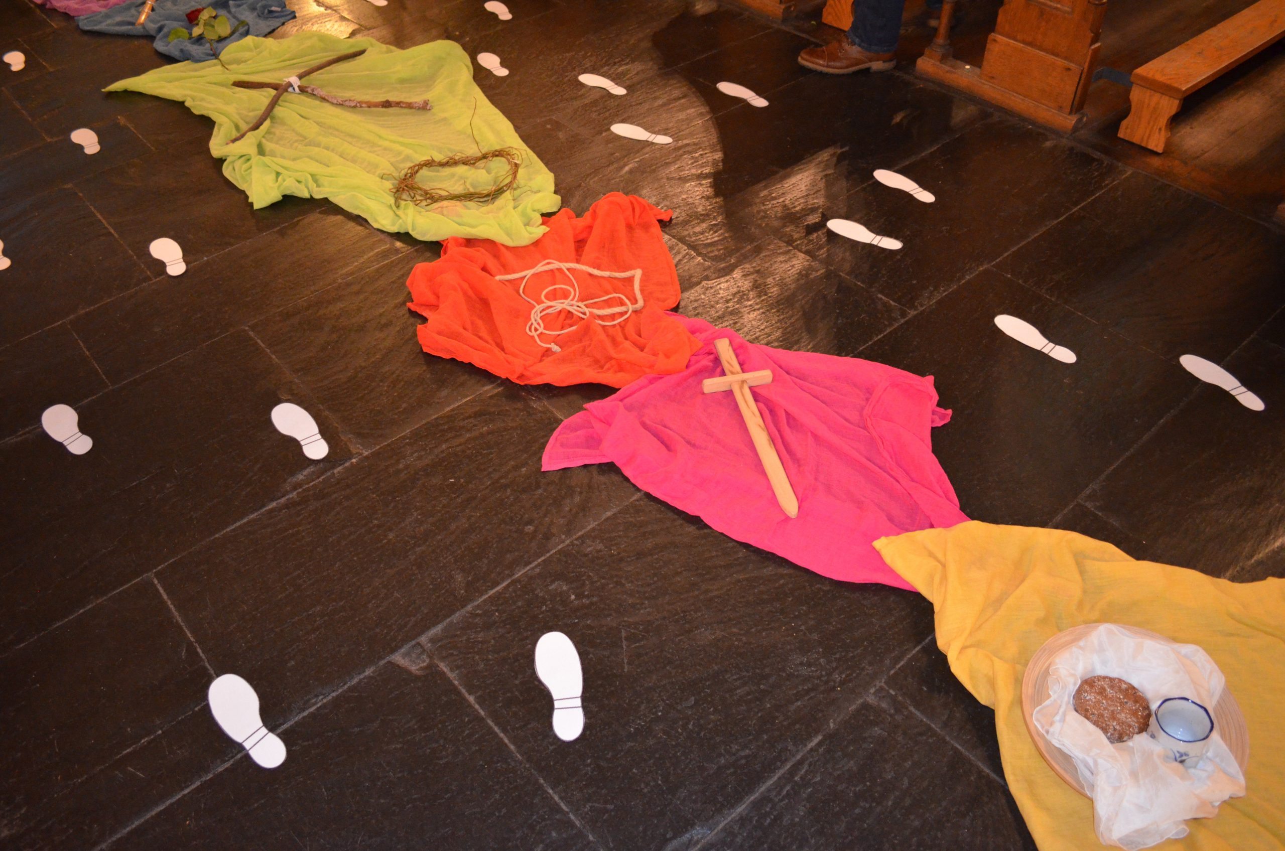 weiße Fußabdrücke, bunte Tücher mit Kreuzen auf dem Boden