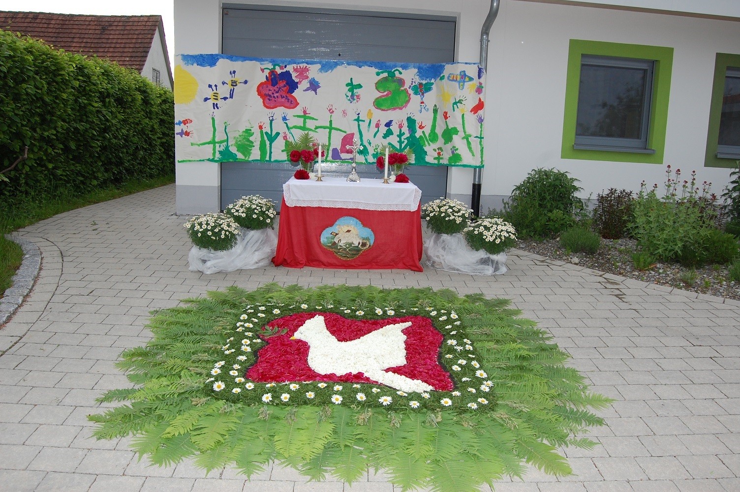 auf dem Bild ist ein Fronleichnamsaltar u. ein Blumenteppich zu sehen